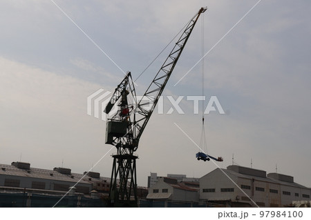 川崎重工業神戸工場のクレーンが車両を吊り上げる風景 97984100