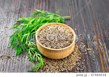 Cumin seeds in bowl with herbs on board Cumin seeds in bowl with herbs on board 97984638