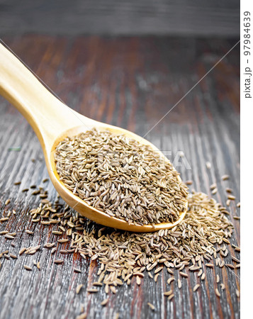 Cumin seeds in spoon on dark wooden board Cumin seeds in spoon on dark wooden board 97984639