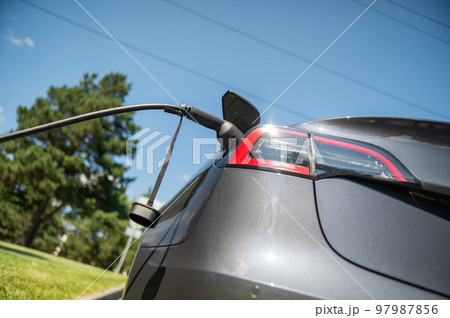 Black electric car charging outdoors in summer. Black electric car charging outdoors in summer. 97987856
