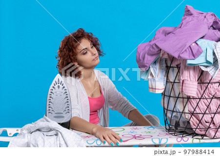 Girl saddened by the large amount of work to be done. Ironing clothes. 97988414