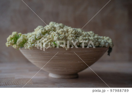Stylish wooden bowl with cauliflower on a marble background Side view. Attractive vegetarian food Stylish wooden bowl with cauliflower on a marble background Side view. Attractive vegetarian food 97988789