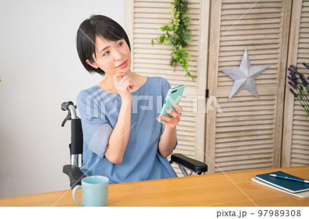 車椅子に座りながらスマートフォンを操作する若い女性 多様性社会イメージ 車椅子に座りながらスマートフォンを操作する若い女性 多様性社会イメージ 97989308