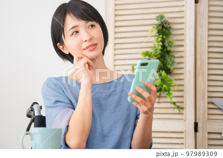 車椅子に座りながらスマートフォンを操作する若い女性 多様性社会イメージ 車椅子に座りながらスマートフォンを操作する若い女性 多様性社会イメージ 97989309