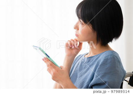 車椅子に座りながらスマートフォンを操作する若い女性 多様性社会イメージ 車椅子に座りながらスマートフォンを操作する若い女性 多様性社会イメージ 97989314