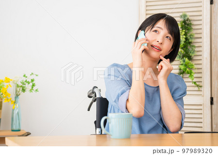 車椅子に座りながら電話をする若い女性 多様性社会イメージ 車椅子に座りながら電話をする若い女性 多様性社会イメージ 97989320