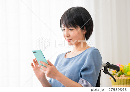 車椅子に座りながらスマートフォンを操作する若い女性 多様性社会イメージ 車椅子に座りながらスマートフォンを操作する若い女性 多様性社会イメージ 97989348