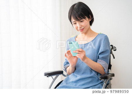 車椅子に座りながらスマートフォンを操作する若い女性 多様性社会イメージ 車椅子に座りながらスマートフォンを操作する若い女性 多様性社会イメージ 97989350