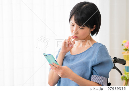 車椅子に座りながらスマートフォンを操作する若い女性 多様性社会イメージ 車椅子に座りながらスマートフォンを操作する若い女性 多様性社会イメージ 97989356