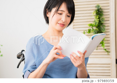 車椅子に座りながらスマートフォンを操作する若い女性　多様性社会イメージ	 97989359