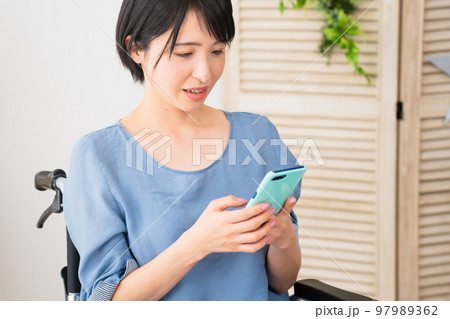 車椅子に座りながらスマートフォンを操作する若い女性 多様性社会イメージ 車椅子に座りながらスマートフォンを操作する若い女性 多様性社会イメージ 97989362
