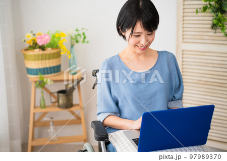 車椅子でノートパソコンを使う若い女性 多様性社会イメージ 車椅子でノートパソコンを使う若い女性 多様性社会イメージ 97989370