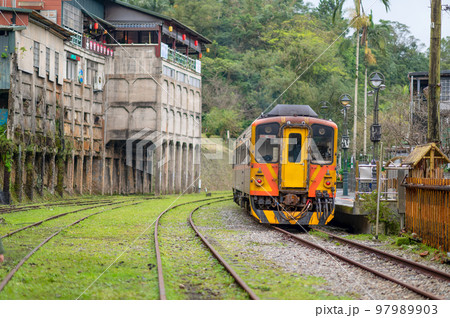 The yellow train is parked by the station platform. A small station on the hill. The yellow train is parked by the station platform. A small station on the hill. 97989903