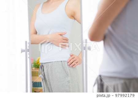鏡でウェストをチェックする若い女性 ダイエットイメージ 鏡でウェストをチェックする若い女性 ダイエットイメージ 97992179