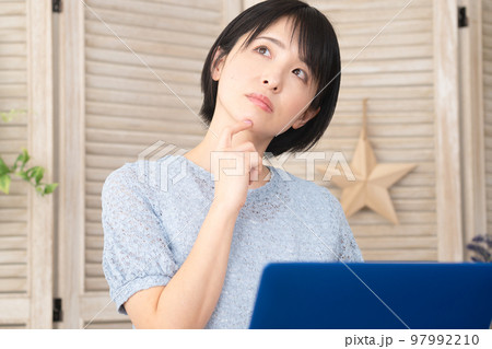 ノートパソコンの前で考え事をする若い女性 ノートパソコンの前で考え事をする若い女性 97992210