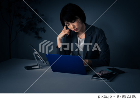 残業をする若いビジネスウーマン　頭痛イメージ	 97992286