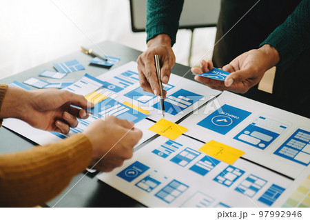 UX developer and ui designer brainstorming about mobile app interface wireframe design with customer breif and color code at office... 97992946