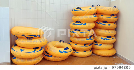 Stacks of yellow water tubes, lying near a light tiled wall 97994809