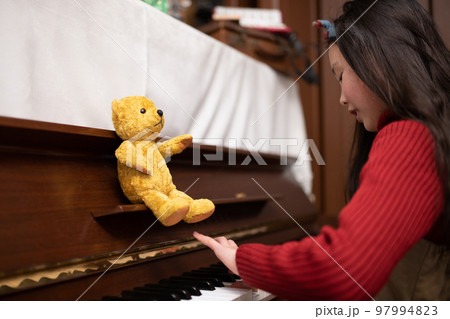 子供にピアノを教える熊の縫いぐるみ 97994823