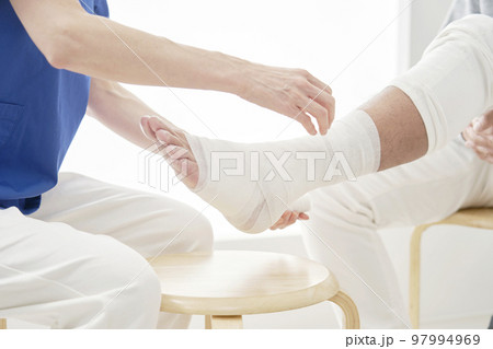 足に包帯を巻く医師　顔無し 97994969