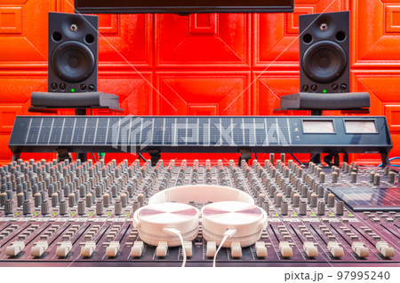 white headphone on audio mixing console, studio monitors background. recording and music production concept 97995240