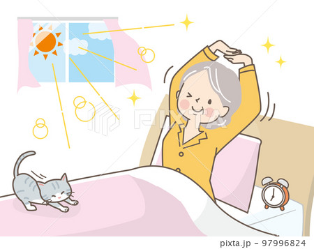 朝スッキリ目覚めて猫と一緒に伸びをするシニア女性 97996824