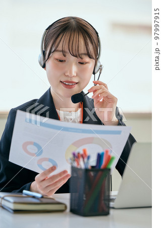 オフィスで電話対応をする若い女性 オフィスで電話対応をする若い女性 97997915