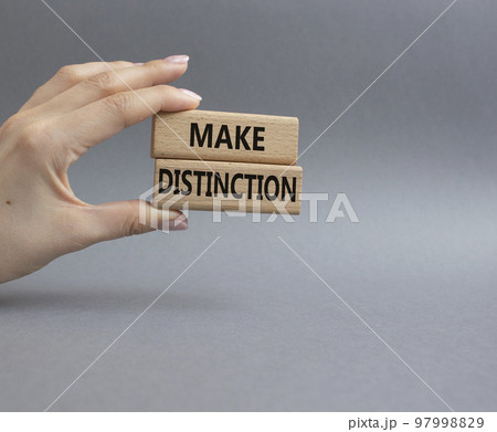 Make distinction symbol. Concept words make distinction on wooden blocks. Beautiful grey background. Businessman hand. Business and make distinction concept. Copy space. 97998829