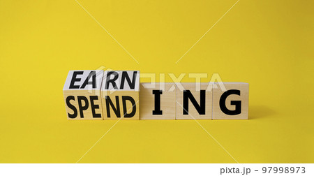 Earning and Spending symbol. Turned cubes with words Earning and Spending. Beautiful yellow background. Business and Earning and Spending concept. Copy space Earning and Spending symbol. Turned cubes with words Earning and Spending. Beautiful yellow background. Business and Earning and Spending concept. Copy space 97998973