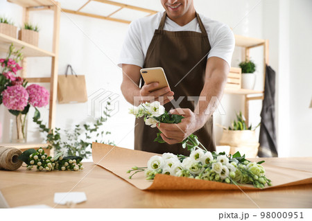 Florist taking picture of beautiful flowers in workshop, closeup Florist taking picture of beautiful flowers in workshop, closeup 98000951