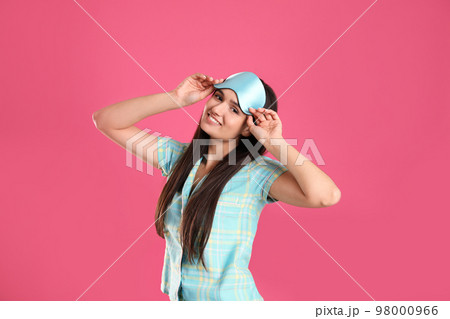 Beautiful woman wearing sleeping mask on pink background. Bedtime Beautiful woman wearing sleeping mask on pink background. Bedtime 98000966