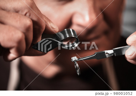 Professional jeweler evaluating beautiful ring, closeup view 98001052