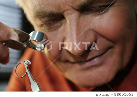 Professional jeweler evaluating beautiful ring in workshop, closeup 98001055