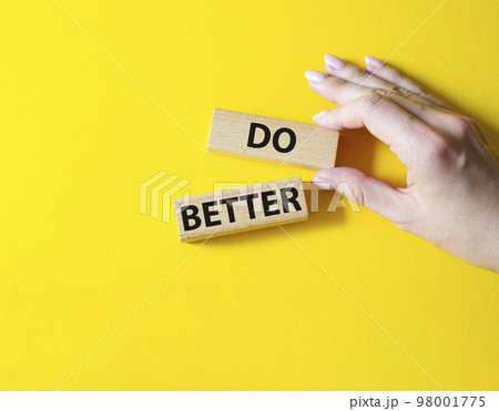 Do better symbol. Wooden blocks with words Do better. Beautiful yellow background. Businessman hand. Business and Do better concept. Copy space. 98001775