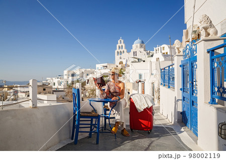 Young woman is sitting at a table and reading a book 98002119
