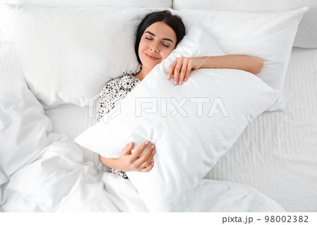 Young woman with pillow in bed, top view. Lazy morning Young woman with pillow in bed, top view. Lazy morning 98002382