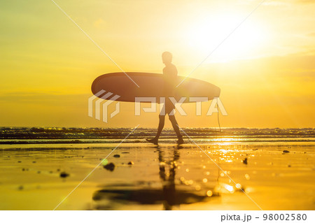 Vacation Silhouette Of A Surfer Carrying His Surf Board Home At Sunset With Copy Space 98002580