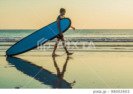 Vacation Silhouette Of A Surfer Carrying His Surf Board Home At Sunset With Copy Space 98002603