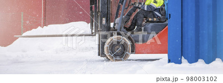 Cargo loader in winter on snow. The loader ride on snow with chains on the wheels to reduce slippage and spin. Driving safety in winter conditions 98003102