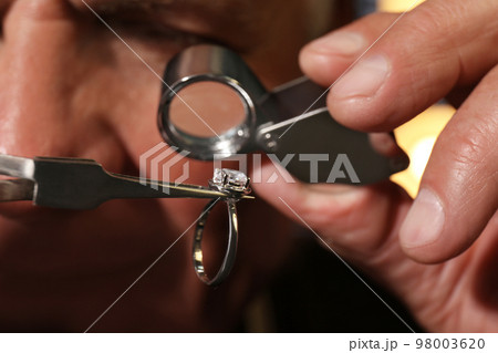 Professional jeweler evaluating beautiful ring, closeup view 98003620