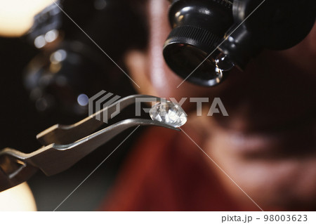 Professional jeweler evaluating beautiful gemstone, closeup view Professional jeweler evaluating beautiful gemstone, closeup view 98003623