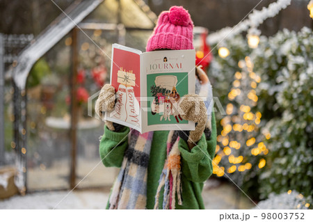 Woman reads magazine at backyard on winter holidays Woman reads magazine at backyard on winter holidays 98003752