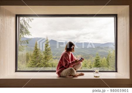 Woman rests in house with scenic views in mountains Woman rests in house with scenic views in mountains 98003901
