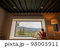 Woman rests in house with scenic views in mountains 98003911