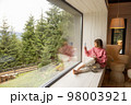 Woman rests in house with scenic view on mountains 98003921