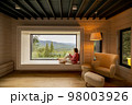 Woman rests in house with scenic view on mountains 98003926