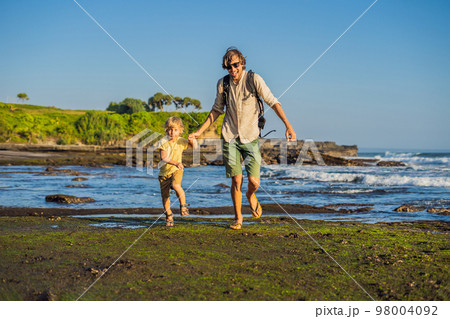 Father and son tourists on the background of Tanah Lot - Temple in the Ocean. Bali, Indonesia. Traveling with children concept Father and son tourists on the background of Tanah Lot - Temple in the Ocean. Bali, Indonesia. Traveling with children concept 98004092