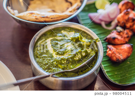 Assorted indian food on dark wooden background. Dishes and appetizers of indian cuisine. Curry, butter chicken, rice, lentils, paneer, samosa, naan, chutney, spices. Bowls and plates with indian food 98004511