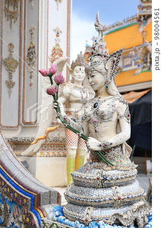 A pearl white statue of NAGA, a Thai mythical goddess holding a bunch of lotus flowers at Wat Pariwat Ratchasongkram. A temple with Thai buddish contemporary art. 98004561