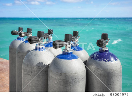 Close up picture of scuba tanks with turquoise water in the background, selective focus. 98004975